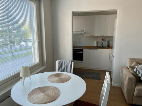 a living room with a white table and a kitchen at Apartment Kustaa in Kokkola