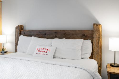 a bed with a wooden headboard with a sign on it at The Bucking Moose in West Yellowstone