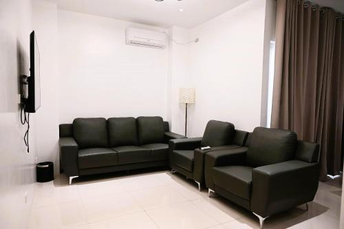 a living room with two black couches and a television at J&V Hotel and Resort in Apaleng