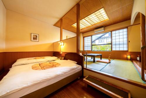 a bedroom with a large bed and a window at Yawaragi-no-Sato Yadoya in Yufuin