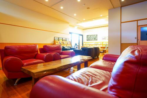 a library with red chairs and a wooden table at Yawaragi-no-Sato Yadoya in Yufuin