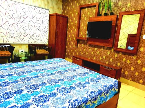 a bedroom with a bed and a tv on the wall at Best Couple Coprtive Guest House in Karachi