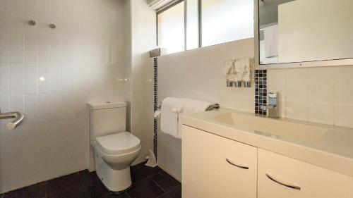 Baño blanco con aseo y lavamanos en Marco Polo Motor Inn Taree, en Taree