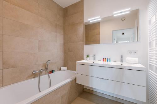 uma casa de banho com uma banheira, um lavatório e um espelho. em Beautifully decorated apartment with sunny terrace em Oostende