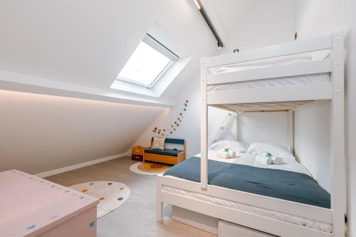 a bedroom with a white bunk bed in a attic at Beautiful modern holiday house with private garden in Bredene