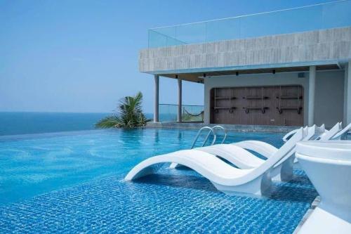 a swimming pool with white lounge chairs in the water at APEC Mandala Cham Bay Mũi Né in Ấp Thiẹn Ái