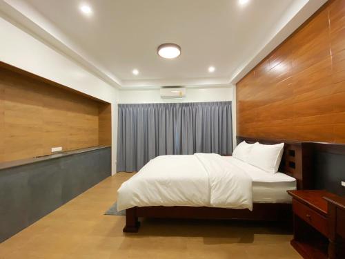 Schlafzimmer mit einem weißen Bett und Holzwänden in der Unterkunft Sanaepatan Home Resort - เสน่ห์ป่าตาล โฮม รีสอร์ต in Ban Buak Khang