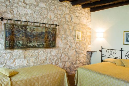 a bedroom with two beds and a stone wall at I Costanti in Caldiero