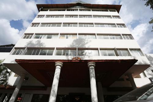 a tall white building with columns in front of it at Super Collection O 9133 The Olive Star in Mysore