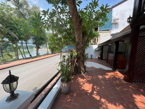 a porch with a tree and a street with a lamp at Golden Lotus Namkhan River View in Luang Prabang