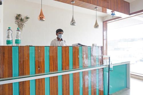 a man wearing a mask behind a counter at OYO Flagship 84218 Hotel Bankar House in Sonai
