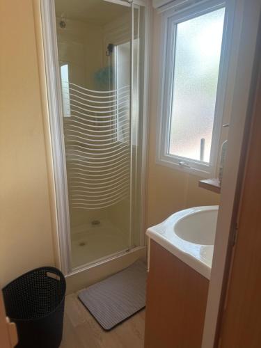 une salle de bain avec douche et lavabo dans l'établissement Mobil home les sables d or, au Grau-dʼAgde