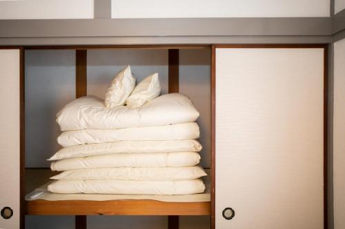a stack of white towels in a closet at Yokkaichi Kawaramachi Hotel in Hazu