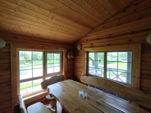 een eetkamer met een houten tafel en 2 ramen bij GREY PINE HOUSE in Druskininkai