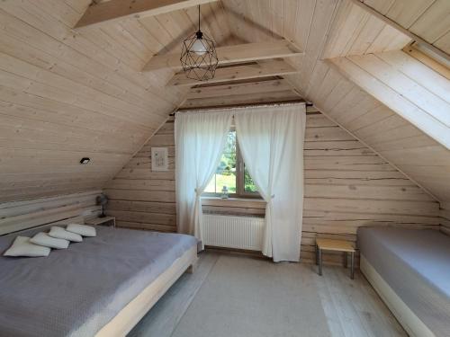 een slaapkamer op zolder met 2 bedden en een raam bij GREY PINE HOUSE in Druskininkai