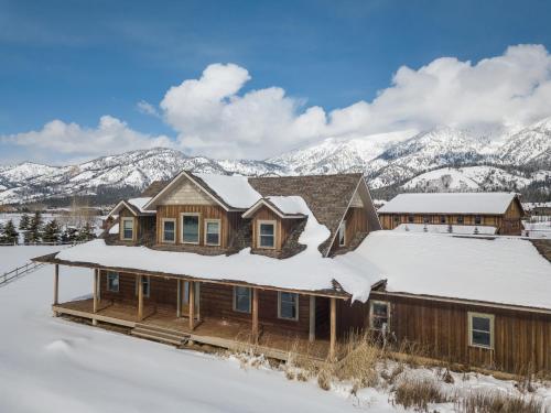 a home covered in snow with mountains in the background at Alpine Airspace by KABINO Airpark Foosball Garage Satellite in Alpine