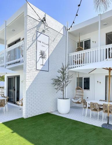 a white brick house with a palm tree sign on it at The Villa's Mooloolaba in Mooloolaba