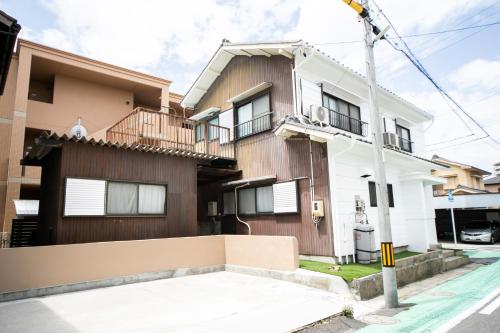 a house with a fence in front of it at Yokkaichi Kawaramachi Hotel in Hazu