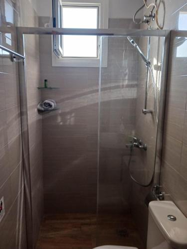 a bathroom with a shower with a toilet and a window at FIORE ROOMS in Akrotiri