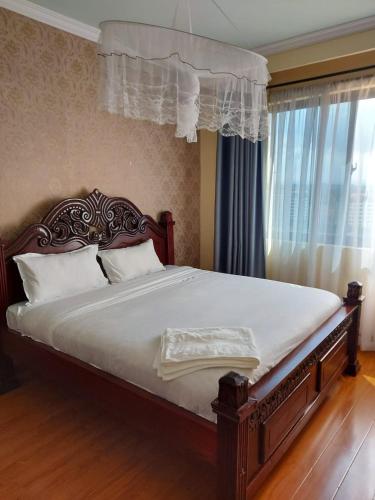 ein Schlafzimmer mit einem großen Bett mit weißer Bettwäsche und einem Fenster in der Unterkunft the heavenly apartments along Dennis prit road. in Nairobi