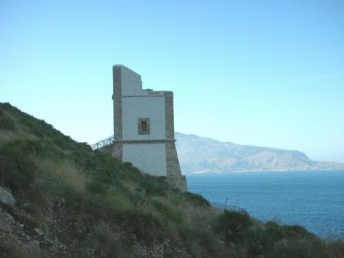 a lighthouse on a hill next to the ocean at Hotel Il Cortile in Custonaci