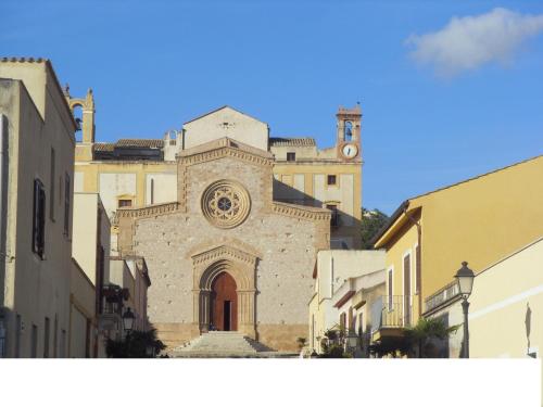 a building with a clock tower in a street at Hotel Il Cortile in Custonaci