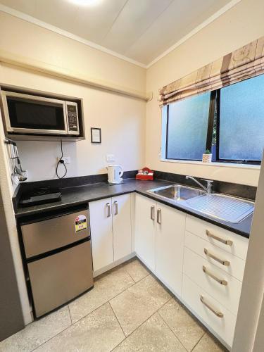 a small kitchen with a sink and a microwave at Kingswood Manor Motel in Whangarei