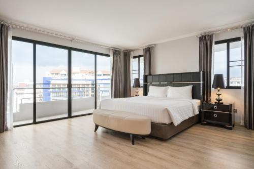 a bedroom with a large bed and large windows at Sirin Exclusive Hotel and Residence in Pattaya South