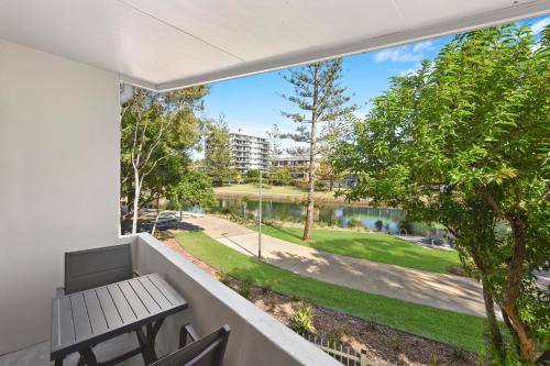 a balcony with a bench and a view of a lake at Palm Court Motor Inn in Port Macquarie