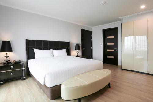a bedroom with a large white bed and a ottoman at Sirin Exclusive Hotel and Residence in Pattaya South