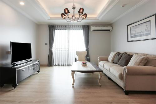 a living room with a couch and a tv at Sirin Exclusive Hotel and Residence in Pattaya South
