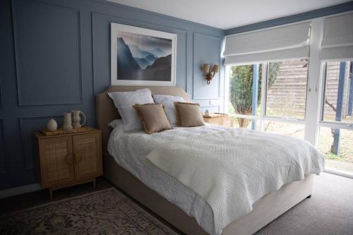 a blue bedroom with a bed and a window at Finsbury House - Luxury 8 Bedroom Farm Homestead with Pool in Kilmore