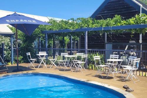 a pool with chairs and tables and an umbrella at Finsbury House - Luxury 8 Bedroom Farm Homestead with Pool in Kilmore