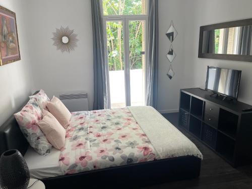 une chambre avec un lit, une télévision et une fenêtre dans l'établissement Chez angy et manu, à Marseille