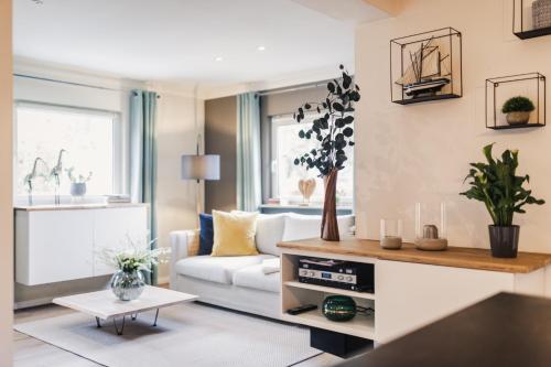 ein Wohnzimmer mit einem weißen Sofa und einem Tisch in der Unterkunft Ferienwohnung "MeerTied" - komfortabel und modern! in Klausdorf