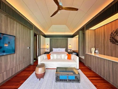 a bedroom with a bed and a ceiling fan at Madifushi Private Island in Meemu Atoll