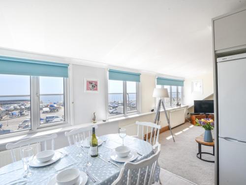 a dining room with a table and chairs and windows at 3 Cobb View in Lyme Regis