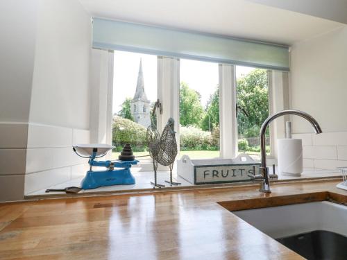a kitchen with a sink and a window with a view of a church at Church View Lower Slaughter in Lower Slaughter