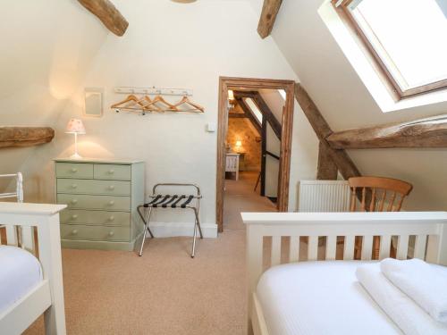 a attic bedroom with two beds and a chair at Church View Lower Slaughter in Lower Slaughter