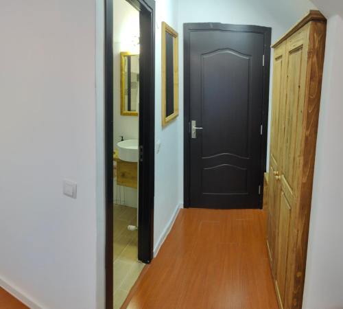a hallway with a black door and a mirror at Pensiunea Trei Brazi Arieseni in Arieşeni