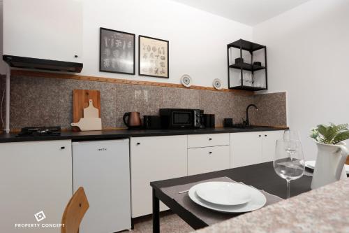 une cuisine avec des placards blancs et un comptoir noir dans l'établissement Stylish Concept Studio, à Bucarest