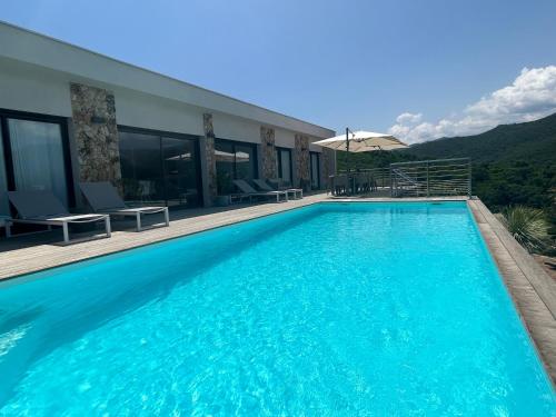 ein großer blauer Pool neben einem Haus in der Unterkunft Villa Pura Corsica with sea view and private pool in Conca