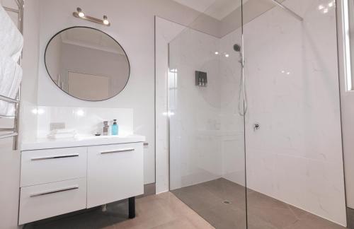 ein Bad mit einer Dusche, einem Waschbecken und einem Spiegel in der Unterkunft Tropicana Motor Inn in Cowes