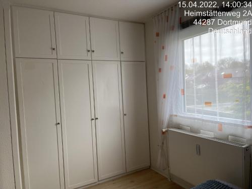 Pokój z białymi szafkami i oknem w obiekcie Wohnung im 2 Familienhaus w Dortmundzie