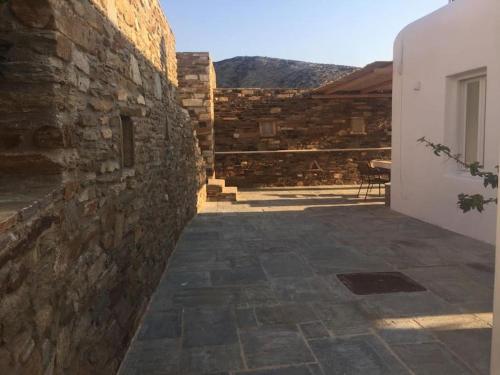 a stone wall next to a building with a patio at Cyclades, villa surplombant la mer in Ios Chora