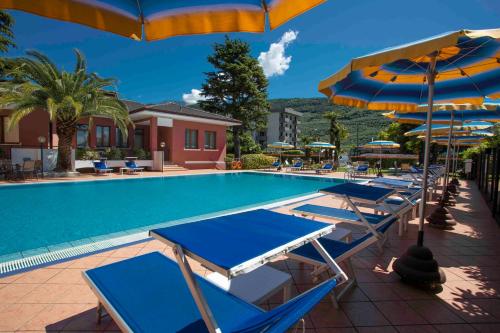 a pool with blue and white chairs and umbrellas at SunLake Hotel in Riva del Garda