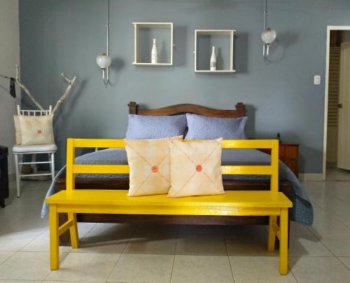 Habitación Casa Las Aves في هوندا: مقعد أصفر مع وسادتين في غرفة النوم