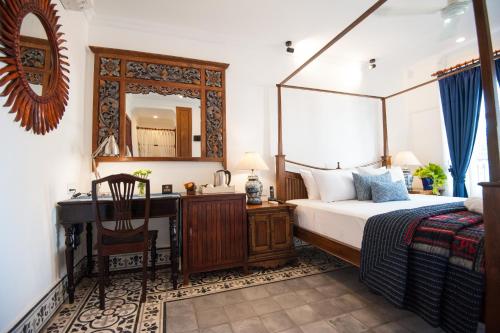 a bedroom with a bed and a desk and a mirror at Khmer Surin Boutique Guesthouse in Phnom Penh