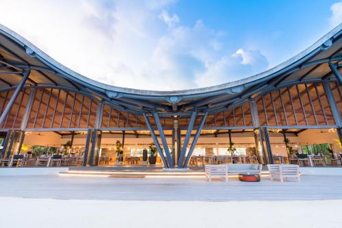 a building with white chairs in front of it at Madifushi Private Island in Meemu Atoll