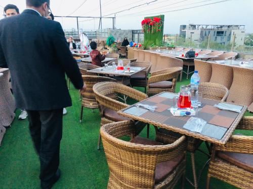 Un homme en costume se promène devant les tables et les chaises dans l'établissement Hotel Oban, à Lahore